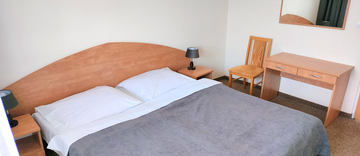 łóżko w sypialni apartamentu obok drewnianej komody